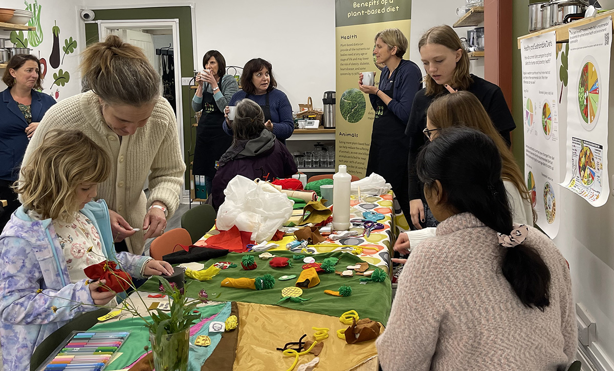 People of all ages standing and sitting around a table with arts and crafts materials.