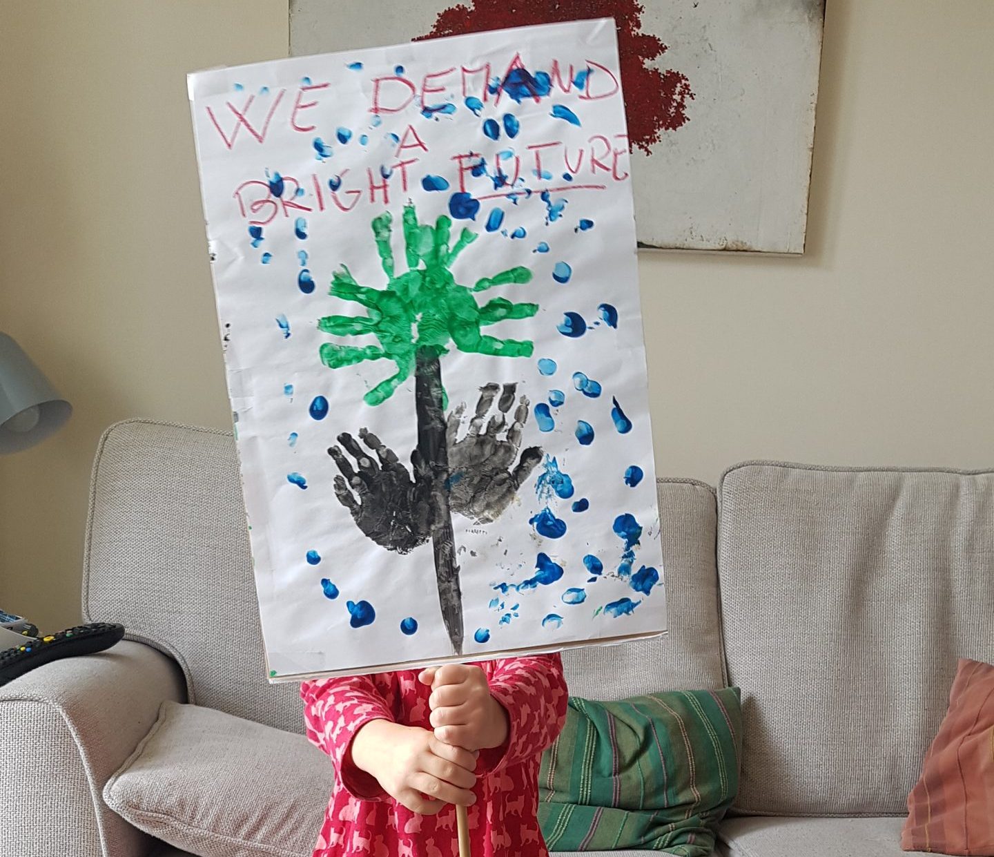 Child holding a placard in front of their face that says "we demand a bright future".