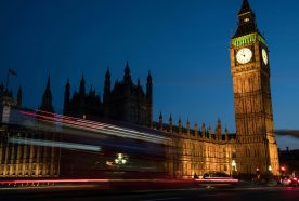 Big Ben, the clock of the house of commons, is seen at dusk with the blurred lights of car passing in front.